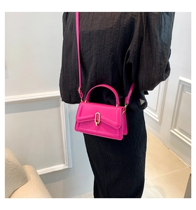 Rose pink handbag with golden U-shaped lock shown on a model in a black dress