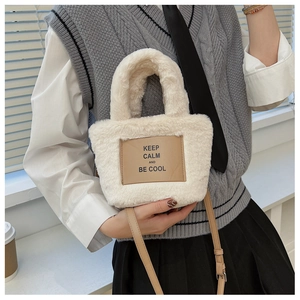 Détail du sac seau en peluche crème avec étiquette en cuir brun et slogan KEEP CALM