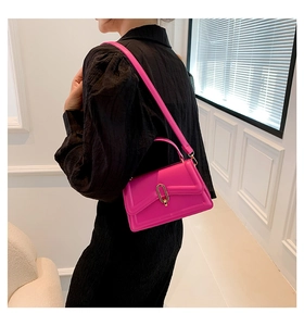 Close-up of bright magenta crossbody bag with golden buckle and textured black top
