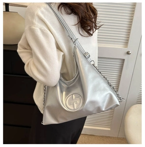 Détail d'un sac cabas argenté métallisé avec chaîne décorative et sangle ajustable