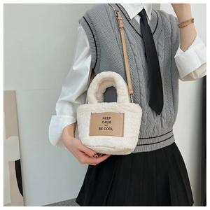 Détail d'un sac seau en peluche blanche avec écusson en cuir et message inspirant