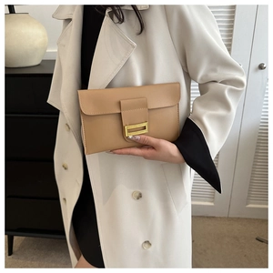 Detail of a chic khaki envelope clutch with a gold buckle held in a modern setting