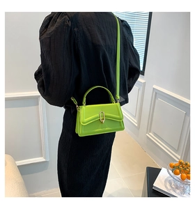 Detail of neon green leather handbag with gold U-shaped buckle on black dress
