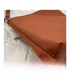 Detail shot of brown lychee texture leather bucket bag with gunmetal ring hardware