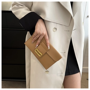 Detail view of khaki envelope clutch bag with gold rectangular metal buckle on trench coat