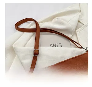 Detail view of adjustable shoulder strap and hardware on brown leather bucket bag