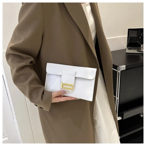 Detail view of a white glossy leather envelope clutch with a gold metal buckle