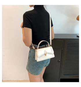 Detail of cream leather crossbody bag with U-shaped gold buckle and shoulder strap