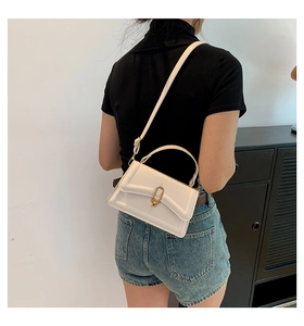 Rear view of model wearing white minimalist crossbody bag with gold lock and thin strap