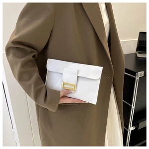 Detail of white envelope clutch with golden metal buckle and textured leather finish