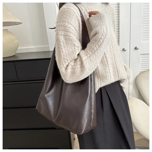 Detail einer dunkelbraunen Leder-Shopper-Tasche kombiniert mit Strickpullover für den Alltag