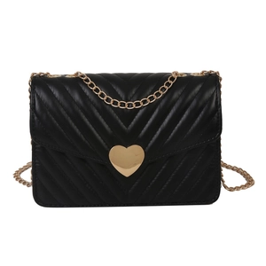 Sac bandoulière noir matelassé en V avec boucle cœur dorée sur fond blanc pur
