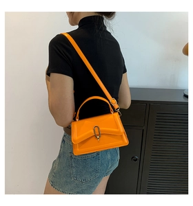 Side view of trendy orange crossbody bag with gold buckle and adjustable strap on a model