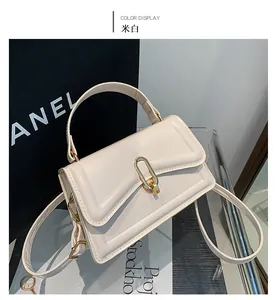 Detail of cream white crossbody bag with elegant gold clasp and wide top handle