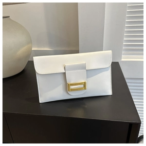 Detail of white minimalist envelope clutch with golden metal clasp on black surface