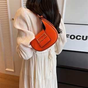 Fashionable orange crescent underarm bag with gold metal buckle shown on a model