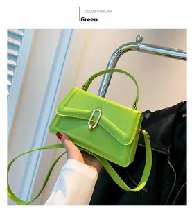 Detail of a bright green crossbody bag with a silver U-shaped metal lock and glossy finish