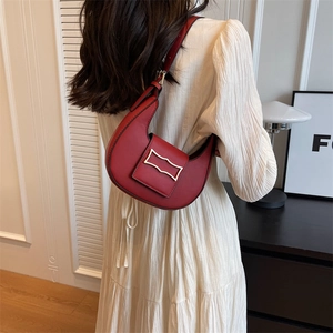 Chic red crescent hobo bag with gold geometric buckle worn over shoulder on model