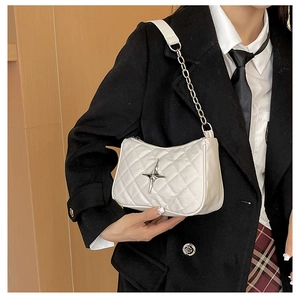 Detail of white quilted underarm bag featuring a metallic silver star and chain strap