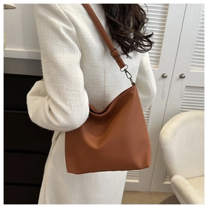 Detail of adjustable strap and gunmetal hook on caramel leather shoulder bag