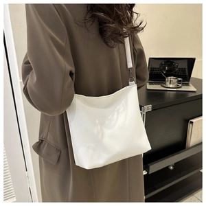 Close-up of a white lychee grain leather crossbody bucket bag worn with an autumn outfit