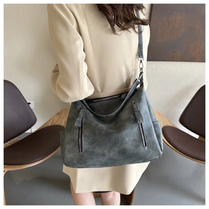 Detail of vintage gray washed leather tote bag with functional pockets on a female model