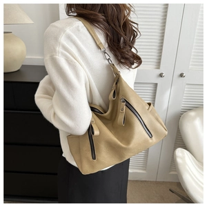 Close-up of a large beige PU leather tote bag with multiple zippers and wide strap