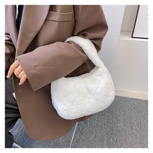 Detail van witte schoudertas van imitatiebont gedragen met een bruine blazer voor herfst