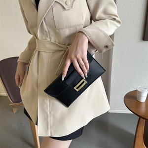 Fashionable black envelope clutch with gold woven buckle paired with beige trench coat