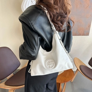Sac hobo blanc minimaliste avec logo embossé et bandoulière chaîne porté par un modèle