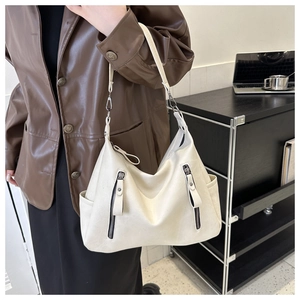 Detail of a creamy white large tote bag with vertical zippers and side pocket on a model