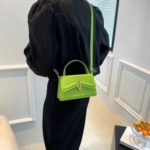 Neon green minimalist crossbody square bag with gold metal clasp on pleated black dress