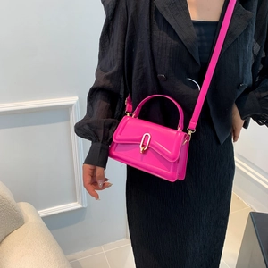 Rose red crossbody bag with top handle and golden buckle worn on black outfit