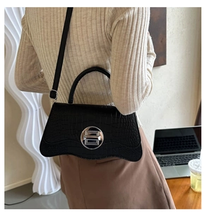 Detail of black crocodile texture bag with wave base and silver round metal lock