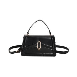 Minimalist black trapezoid leather crossbody bag with oval gold metal buckle and top handle
