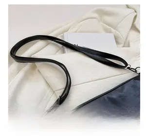 Détail de la bandoulière confortable et des ferrures sur le grand sac seau noir