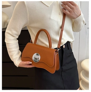 Detailed view of brown crocodile texture handbag featuring silver twist lock and wavy base