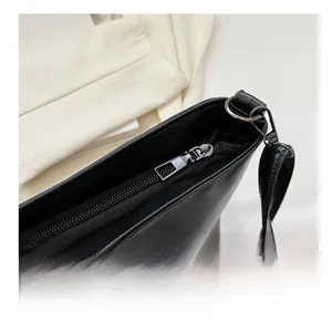 Détail de la fermeture éclair argentée et des boucles métalliques sur le sac à main noir