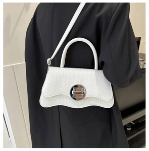 Close-up of a white faux crocodile skin bag with a stylish silver round buckle lock
