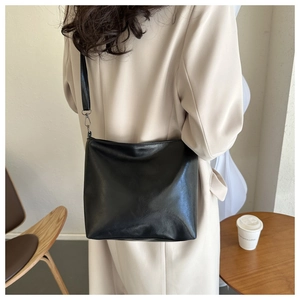 Détail du fourre-tout noir en similicuir montrant la fine bandoulière et le design épuré