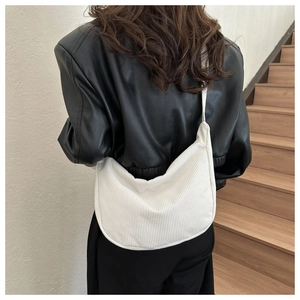 Sac bandoulière en velours côtelé blanc porté par un mannequin avec une veste en cuir noir
