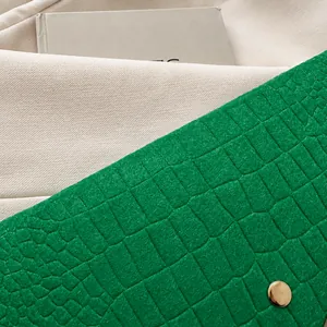 Close-up of green crocodile pattern leather clutch with elegant gold magnetic clasp