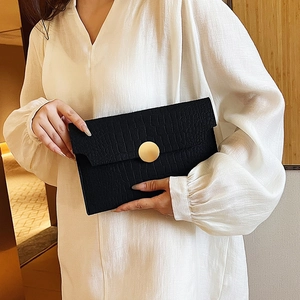 Chic black crocodile embossed envelope clutch bag with a large round gold metal buckle