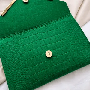 Macro shot of green crocodile texture envelope bag with gold magnetic buckle closure
