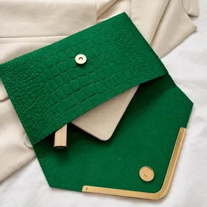 Detail showing inner capacity of green croc-embossed envelope clutch with metal trim