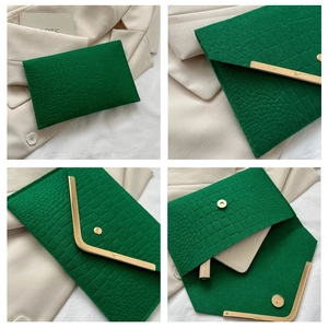 Detail of green crocodile texture envelope bag with gold metal trim and magnetic closure