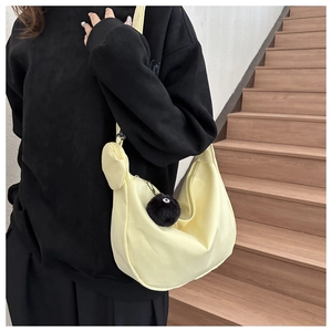 Detail of light yellow half-moon crossbody bag with mini pouch and plush charm