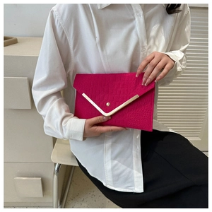Detail of rose red envelope clutch featuring faux crocodile texture and gold V-trim