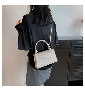Detail of beige pleated crossbody bag showing textured finish and leather strap