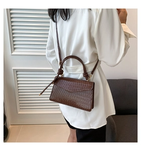 Detail showing deep brown crocodile texture small square handbag with a knotted handle